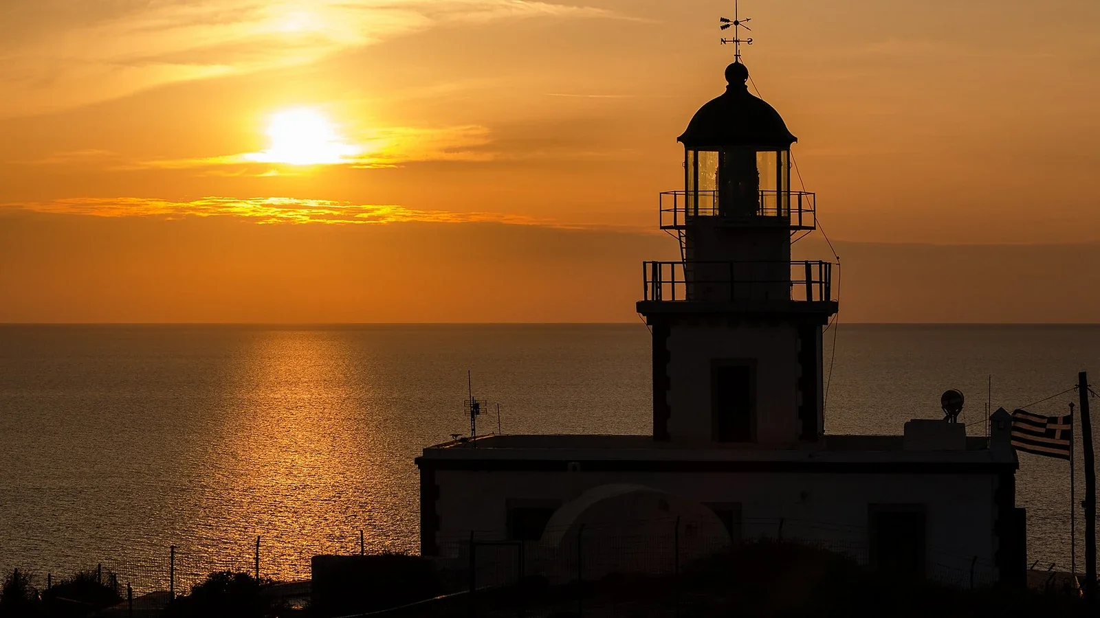 Силуэт маяка Акротири на фоне закатного неба и золотистого моря