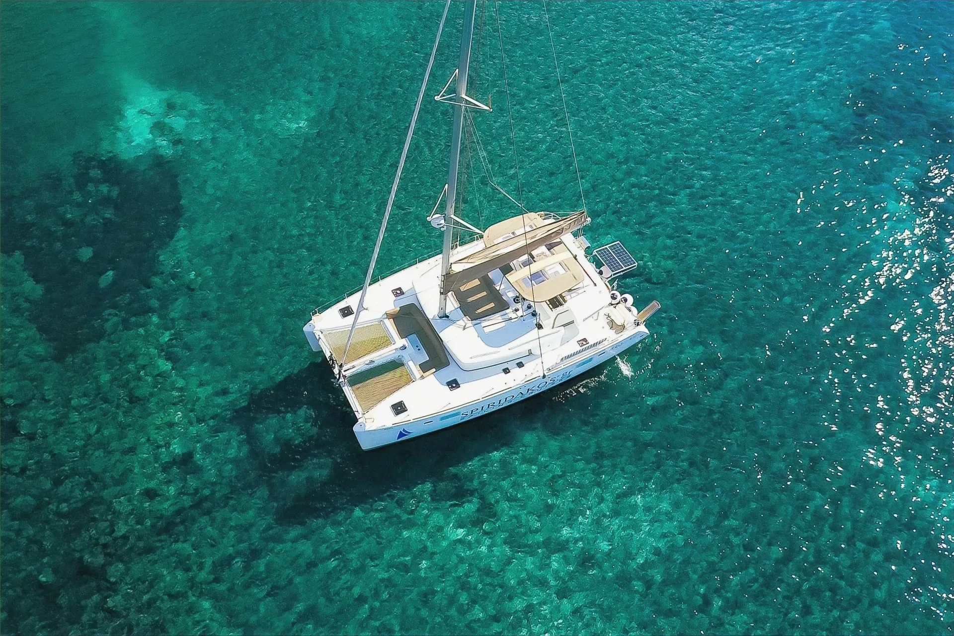 Катамаран на якоре в прозрачной бирюзовой воде у Санторини, вид сверху
